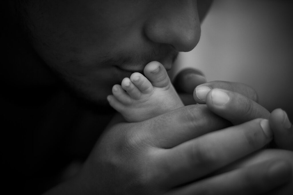parent embrassant les pied de son bébé